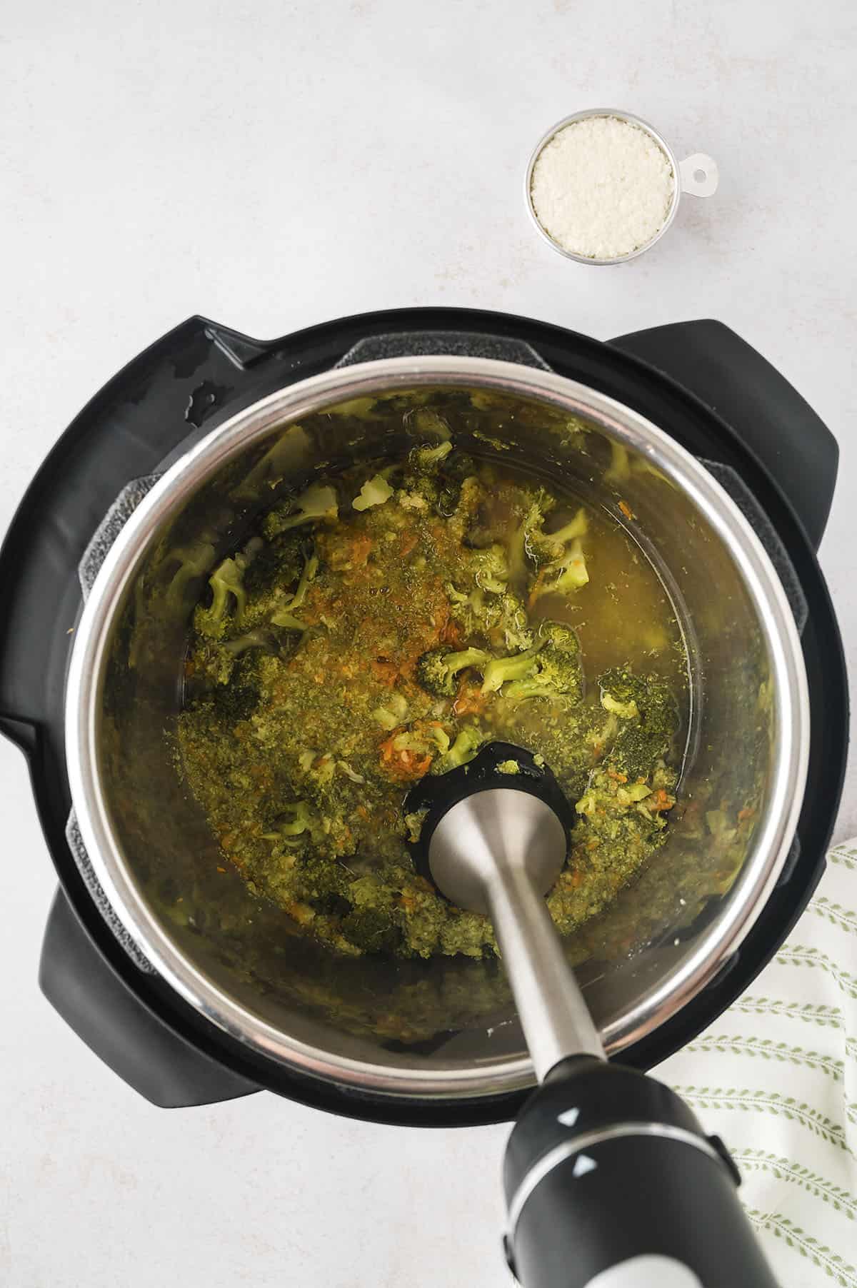 Immersion blender blending broccoli cheddar soup in Instant Pot.