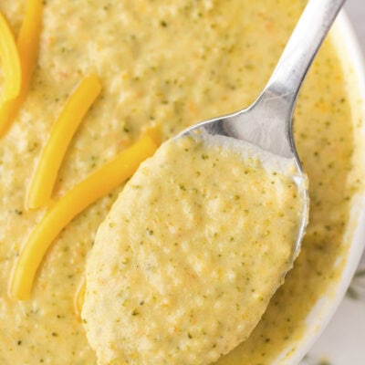 Instant Pot broccoli cheddar soup in white bowl on spoon.