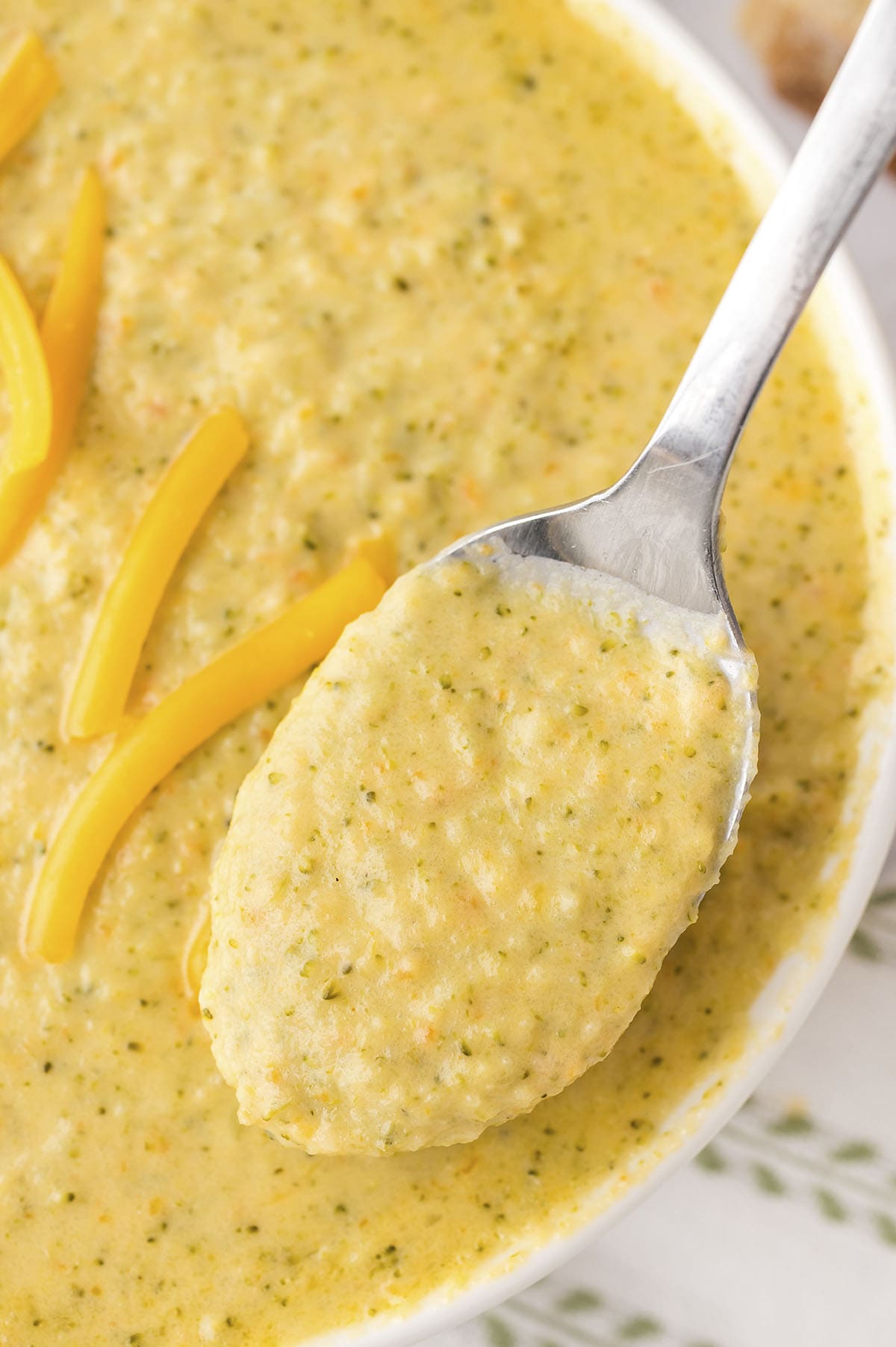 Instant Pot broccoli cheddar soup in white bowl on spoon.