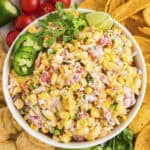 Cold corn dip in bowl surrounded by chips and vegetables.