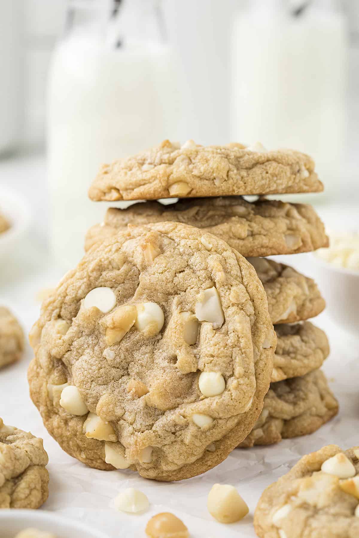 White chocolate macadamia nut cookies stackedi n front of milk.