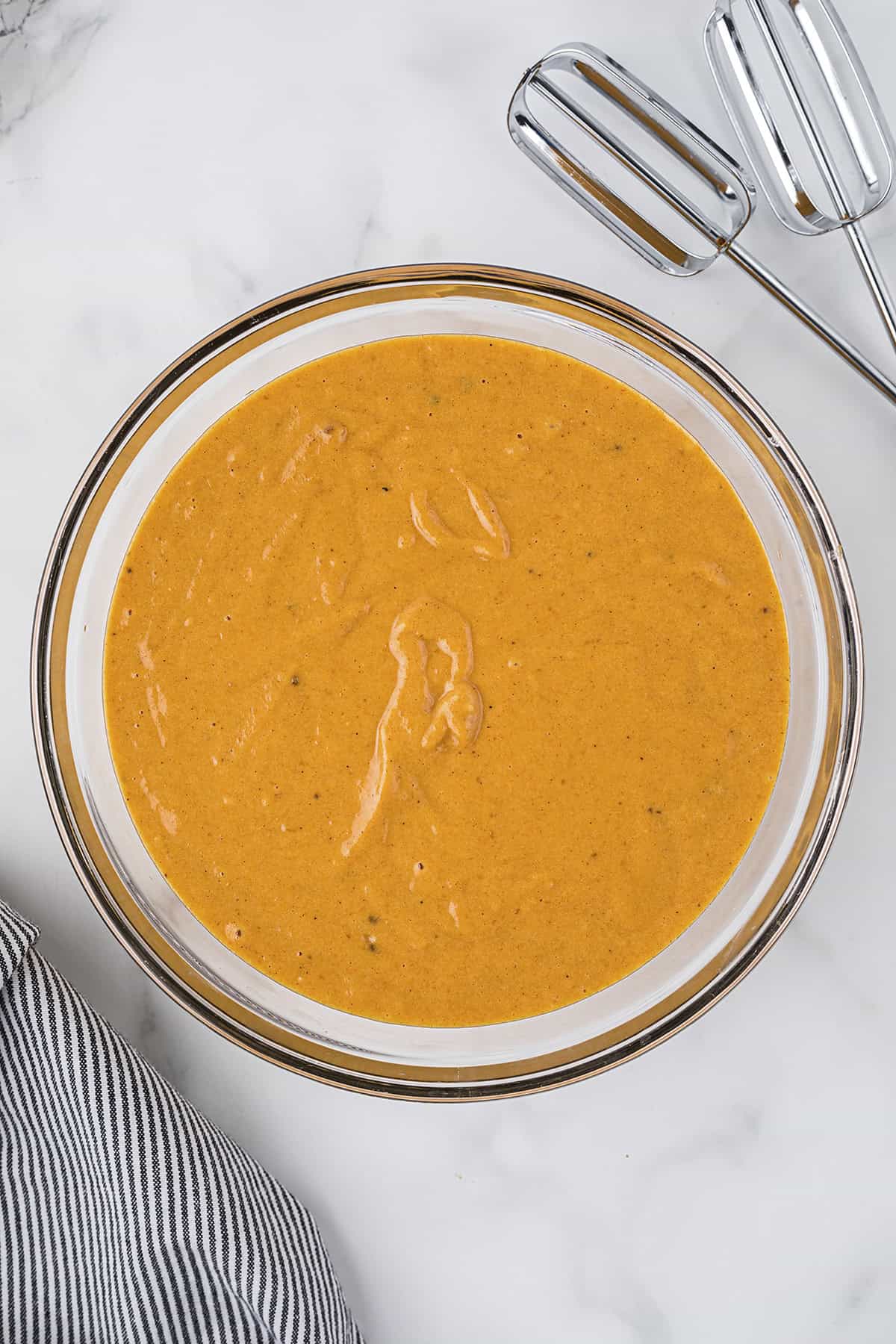 Ingredients for pumpkin cake in glass mixing bowl.