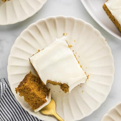 Overhead view of sliced pumpkin cake on white plate.