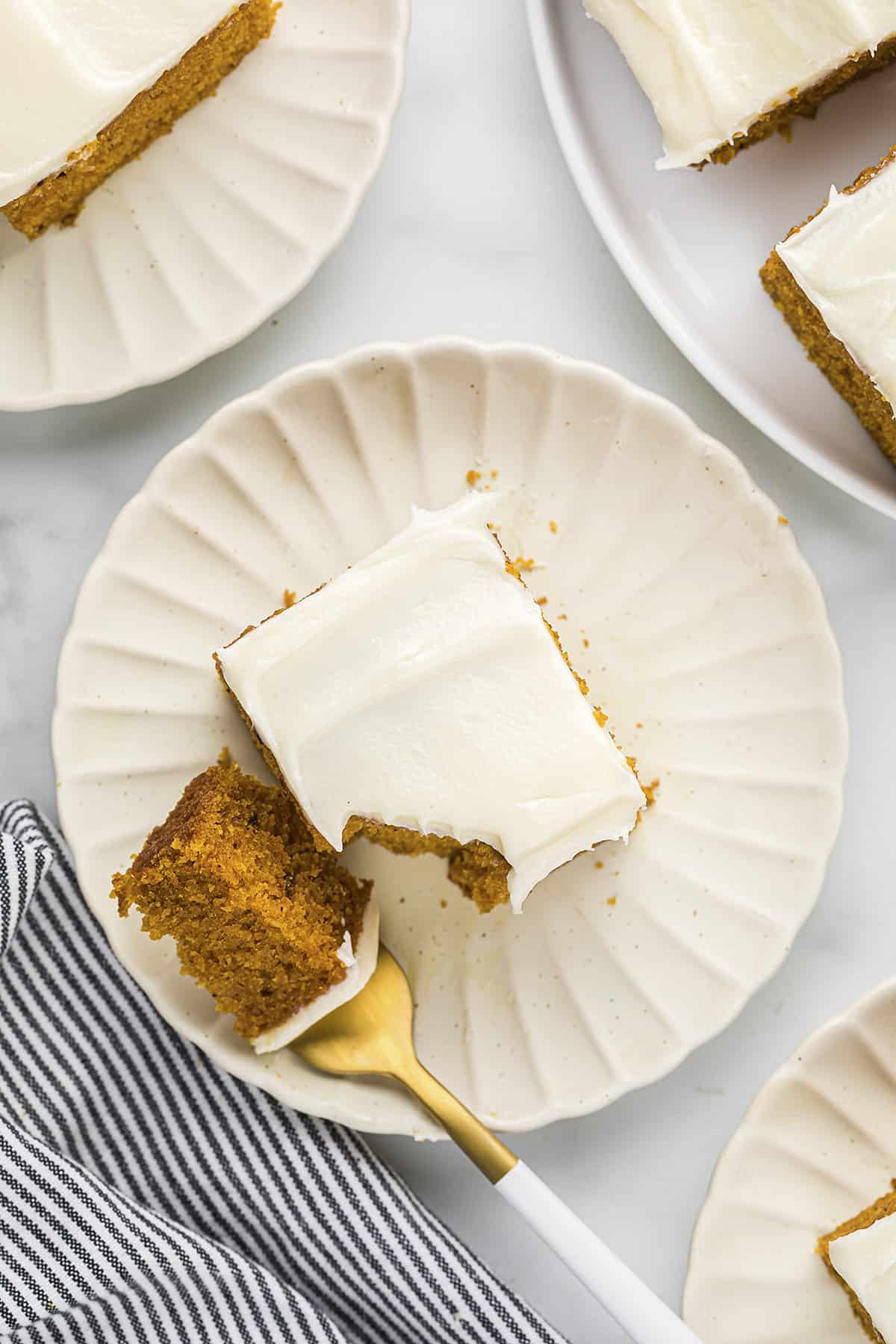 Overhead view of sliced pumpkin cake on white plate.