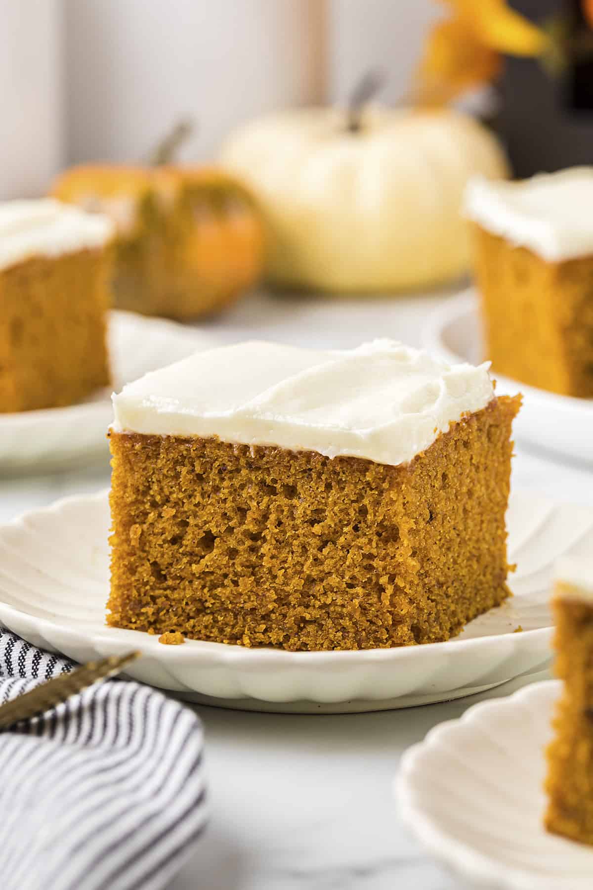 Pumpkin cake with cream cheese frosting on white plates.