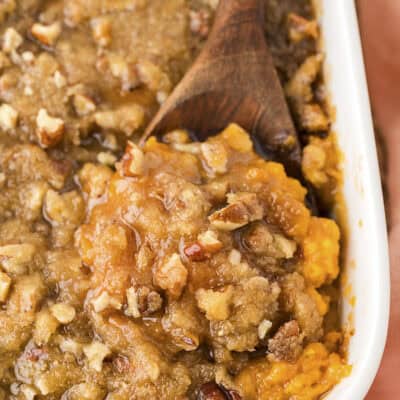 Sweet potato casserole in a white baking dish with a wooden spoon.