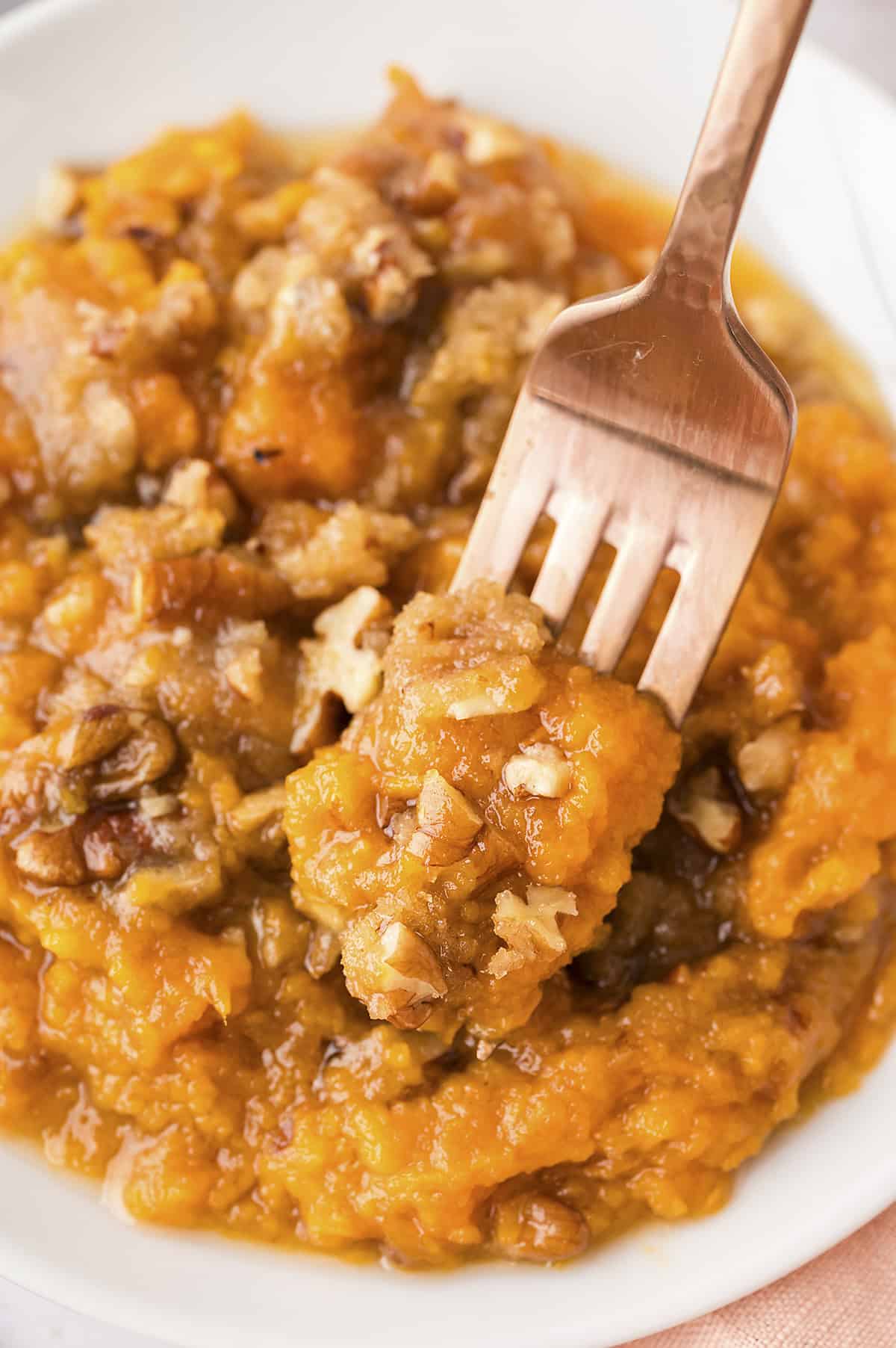 Forkful of Ruth Chris sweet potato casserole on white plate.