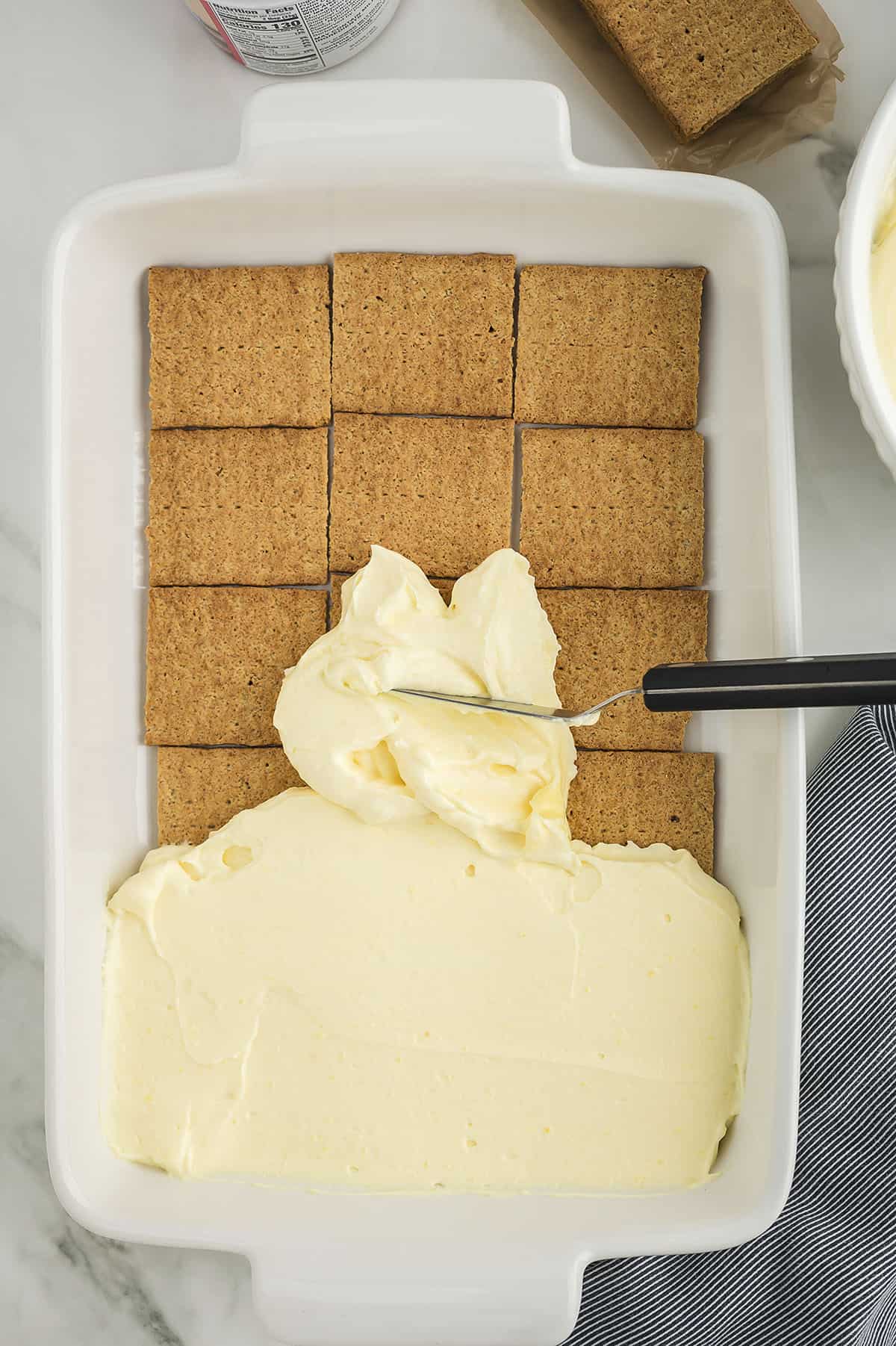 Pudding being spread over graham crackers.