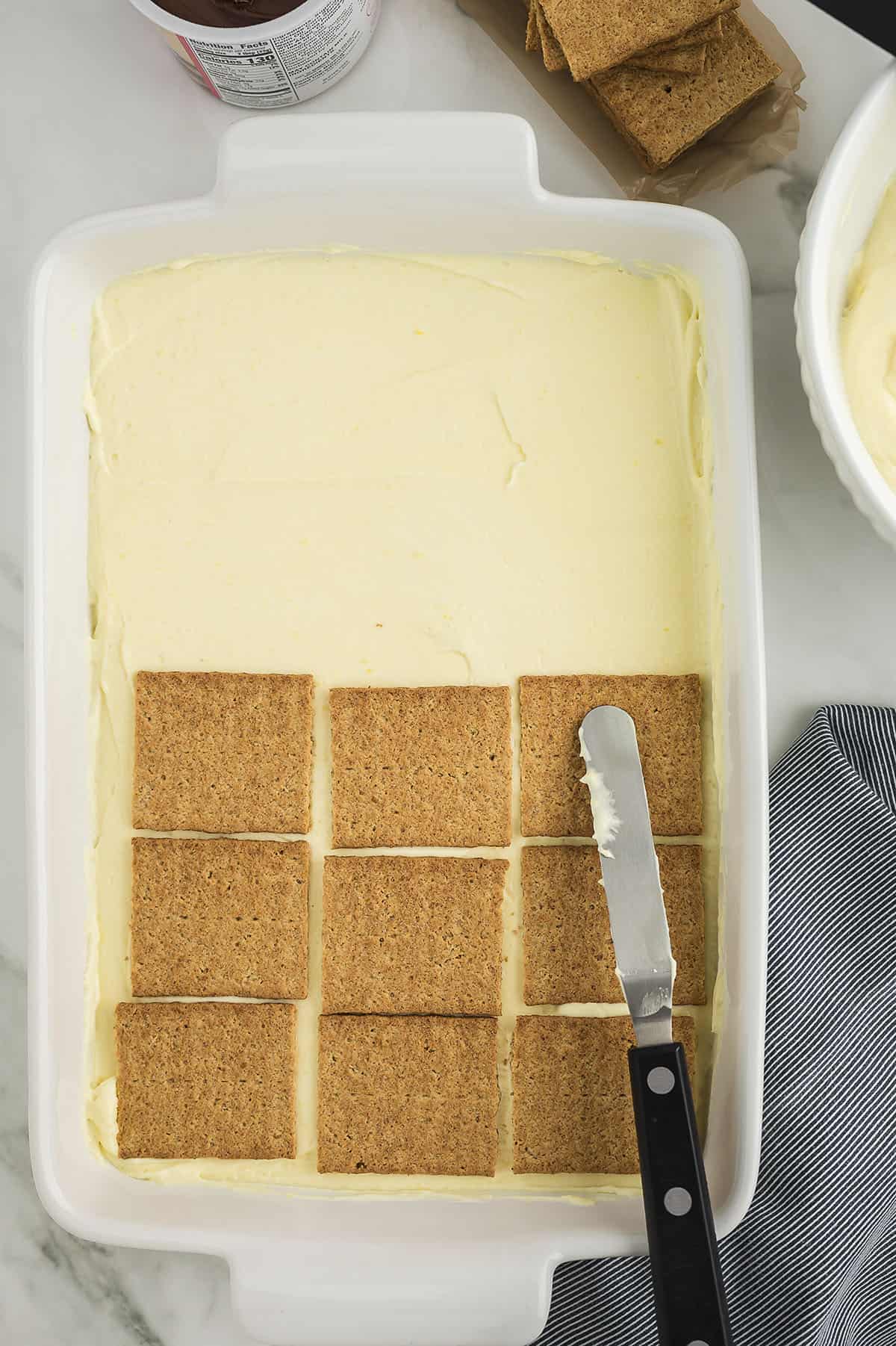 Graham crackers being placed over pudding.