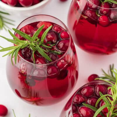 Glasses of Christmas sangria garnished with fresh rosemary.