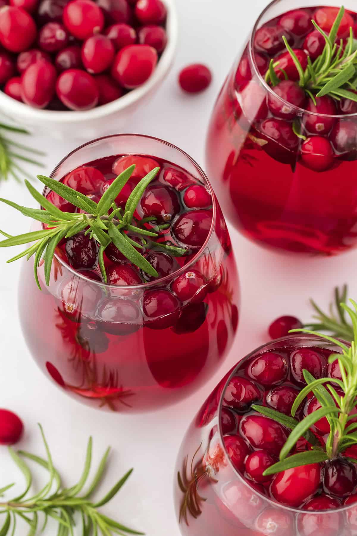 Glasses of Christmas sangria garnished with fresh rosemary.