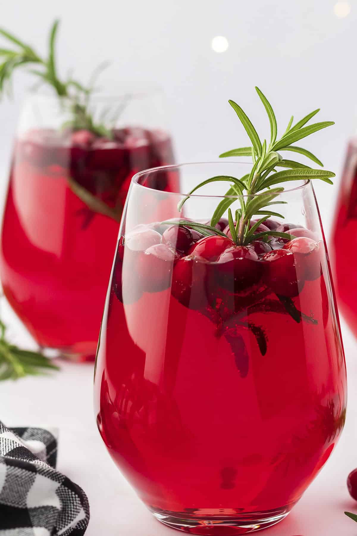 Wine glass full of Christmas sangria topped with cranberries and rosemary.