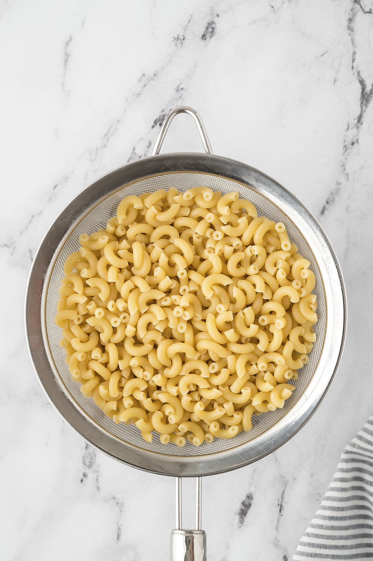 Cooked macaroni in strainer.