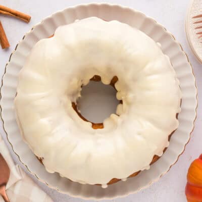 Cream cheese glazed pumpkin bundt cake on cake plate.