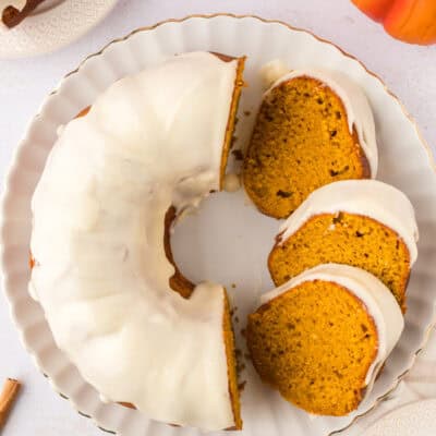 Slices of pumpkin bundt cake with cream cheese glaze on cake platter.