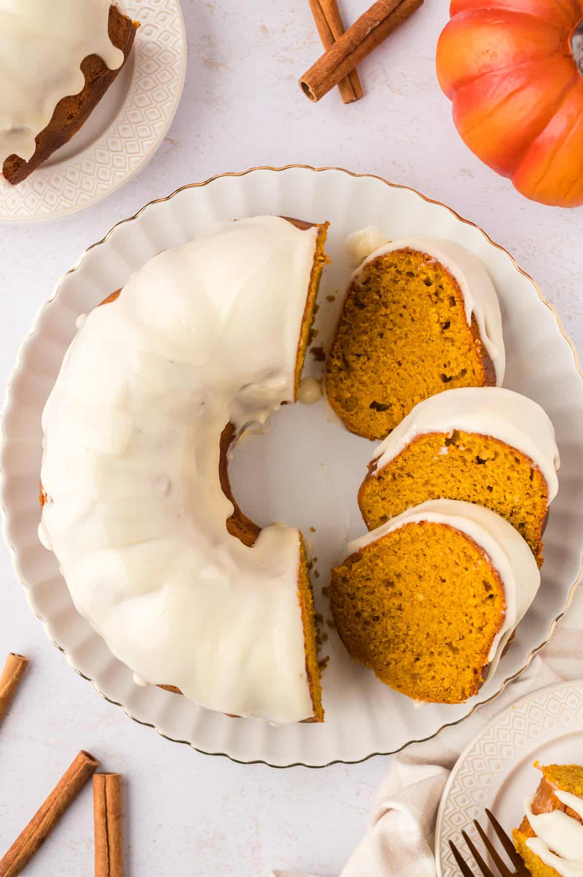 Slices of pumpkin bundt cake with cream cheese glaze on cake platter.