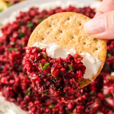 Cracker being dipped into cranberry cream cheese dip.