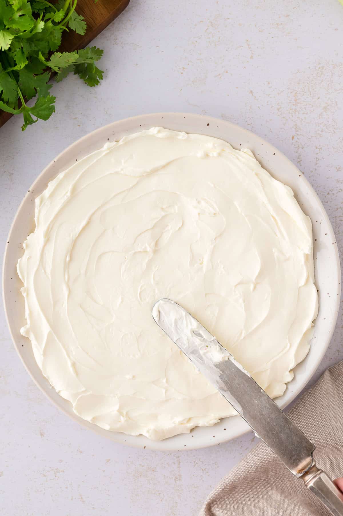 Cream cheese being spread on a plate.