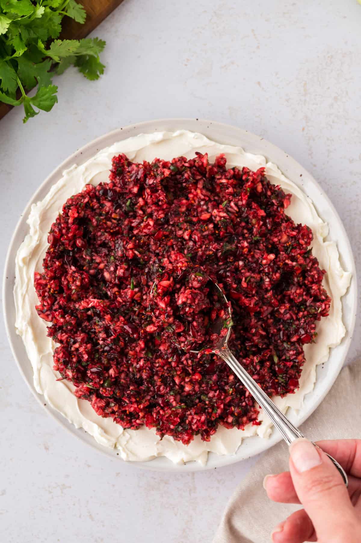 Cranberry salsa being spooned over cream cheese.