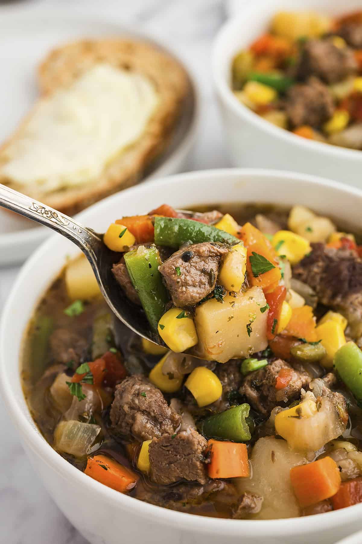 Vegetable beef soup in bowl on spoon.