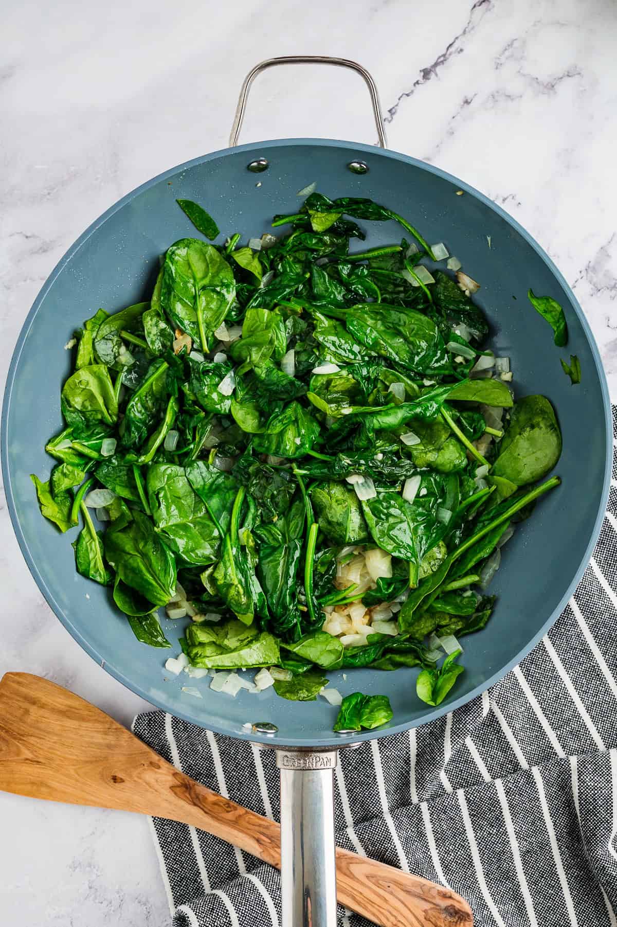 Spinach in a skillet with onions and garlic.