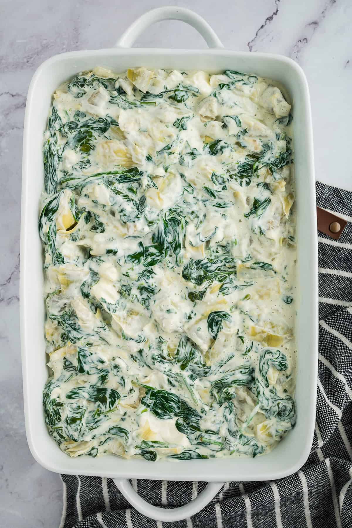 Spinach casserole in white baking dish.