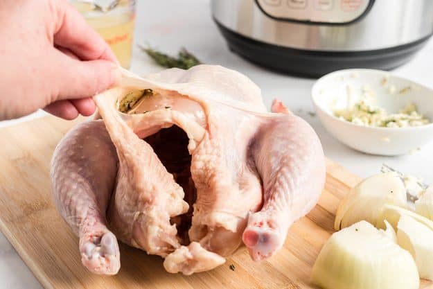 butter mixture being placed under the skin of chicken.