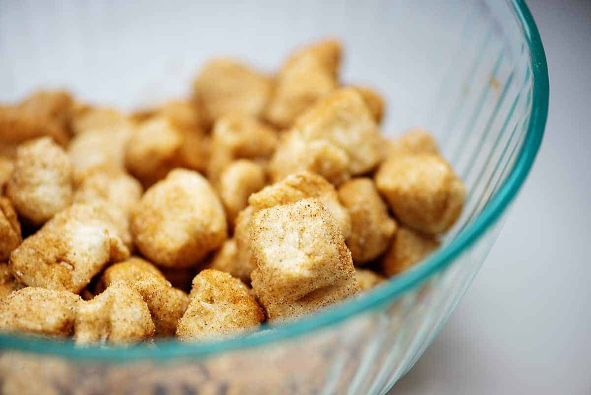 biscuits coated with cinnamon and sugar in glass mixing bowl.