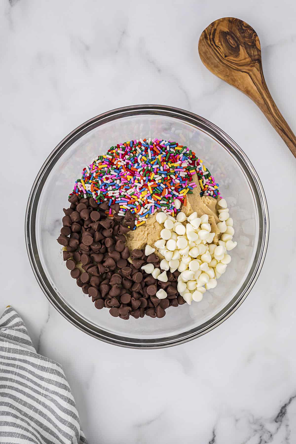 Chocolate chips and sprinkles in mixing bowl with cookie dough.