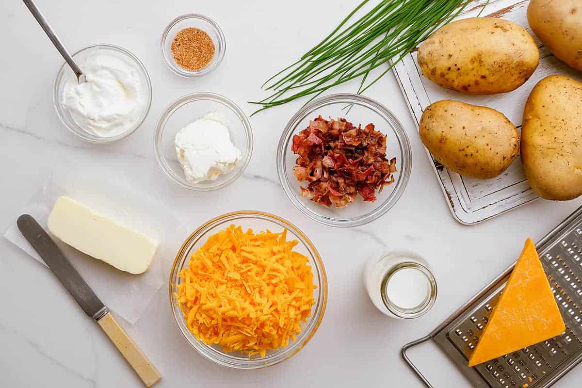 ingredients for twice baked potatoes on white counter.