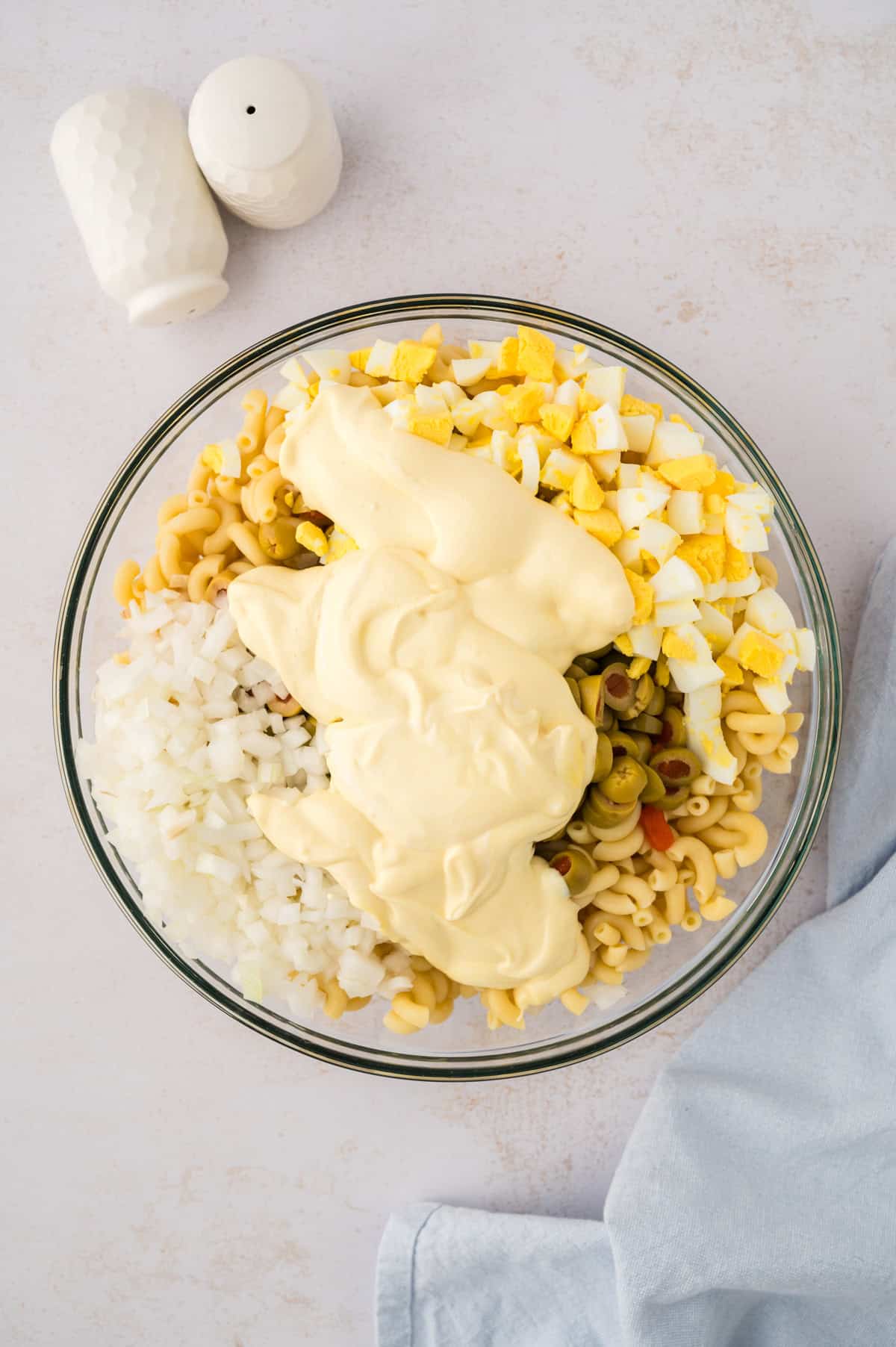 Macaroni salad dressing poured over pasta.