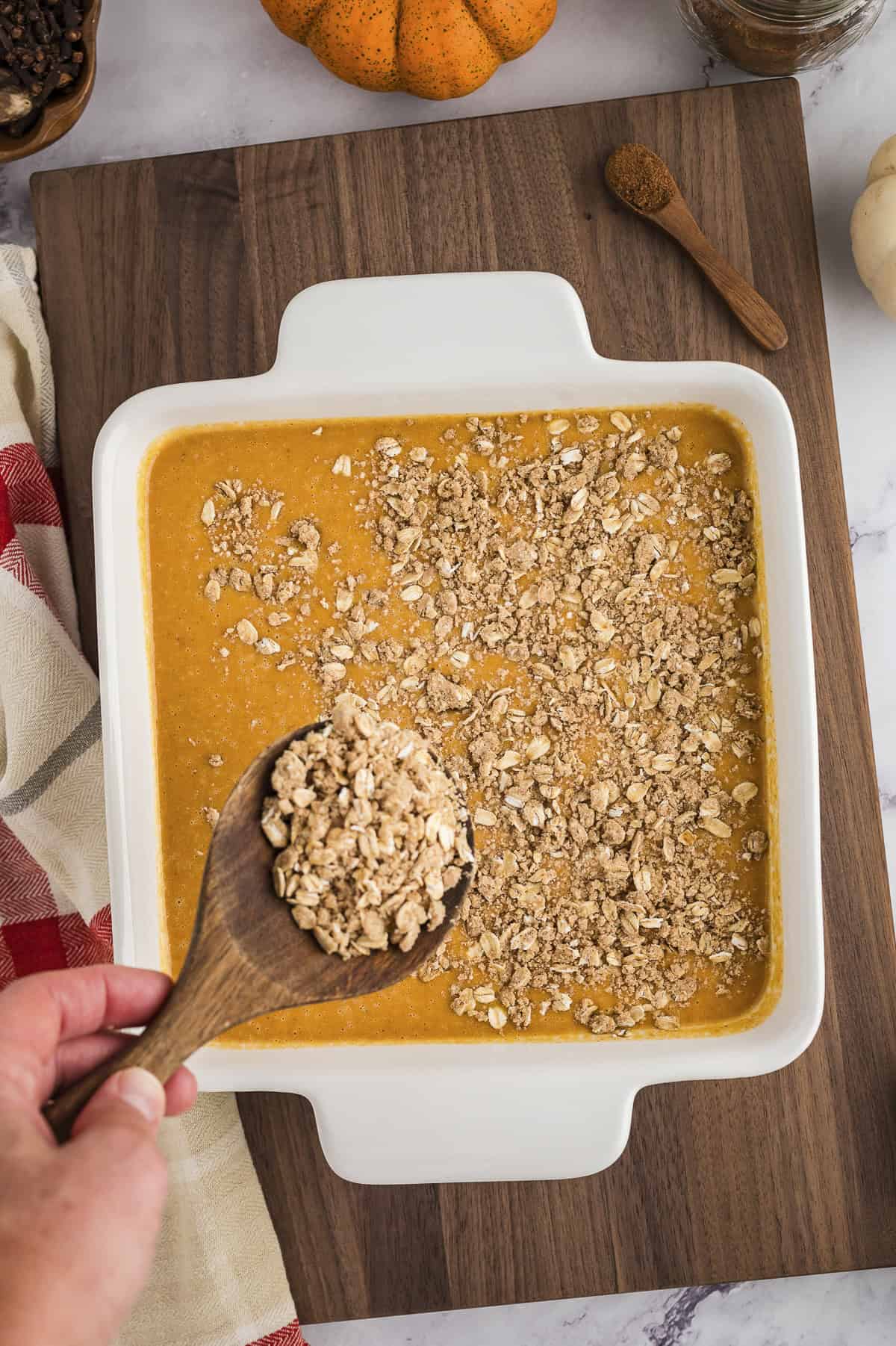 Topping being sprinkled over pumpkin filling.