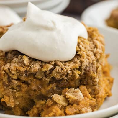 Pumpkin crisp topped with whipped cream on small plate.