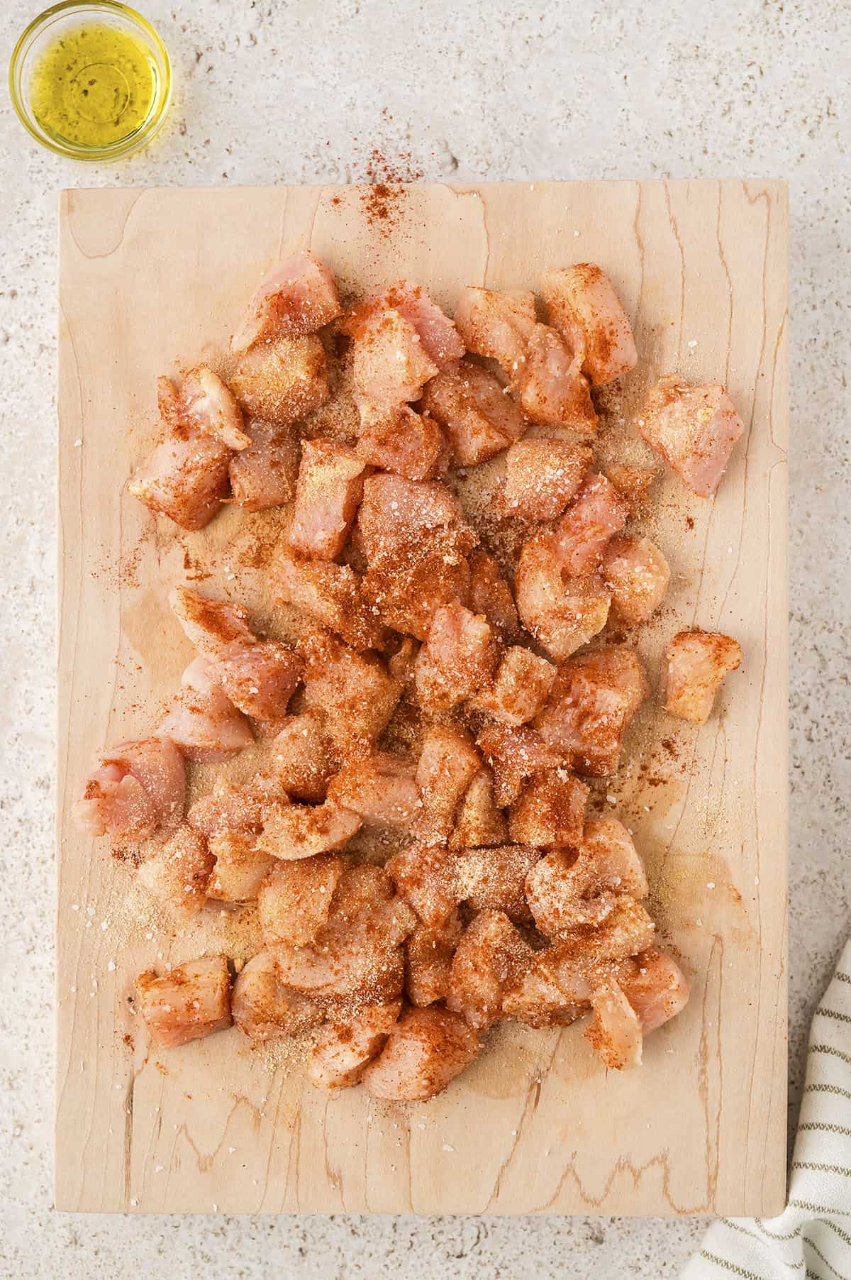 Seasoned chunks of chicken on cutting board.