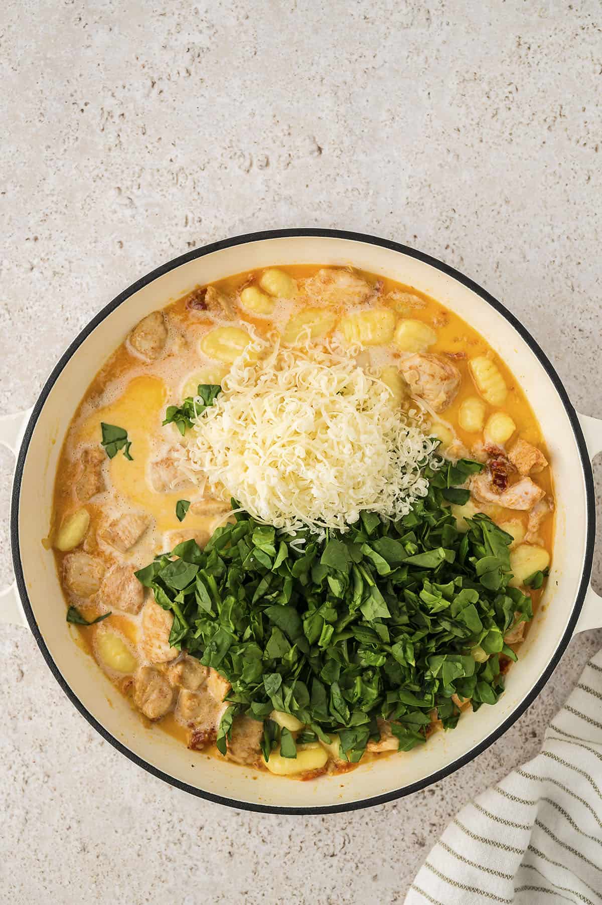 Spinach and parmesan in pot of gnocchi.