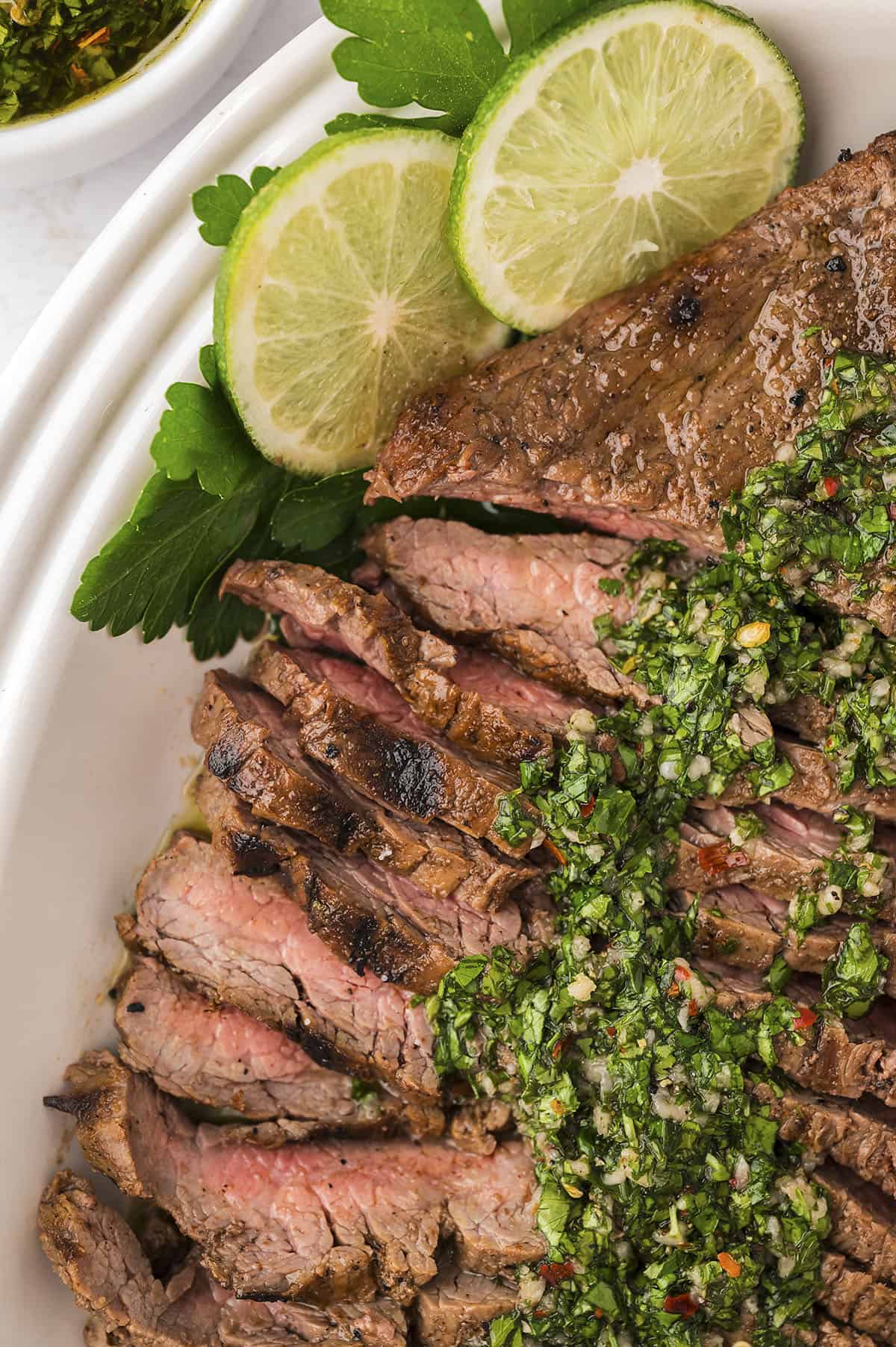 Close up of sliced flank steak topped with cilantro chimichurri.