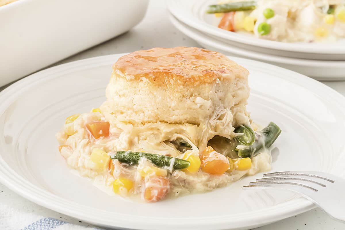 Homemade chicken pot pie with biscuit on white plate.