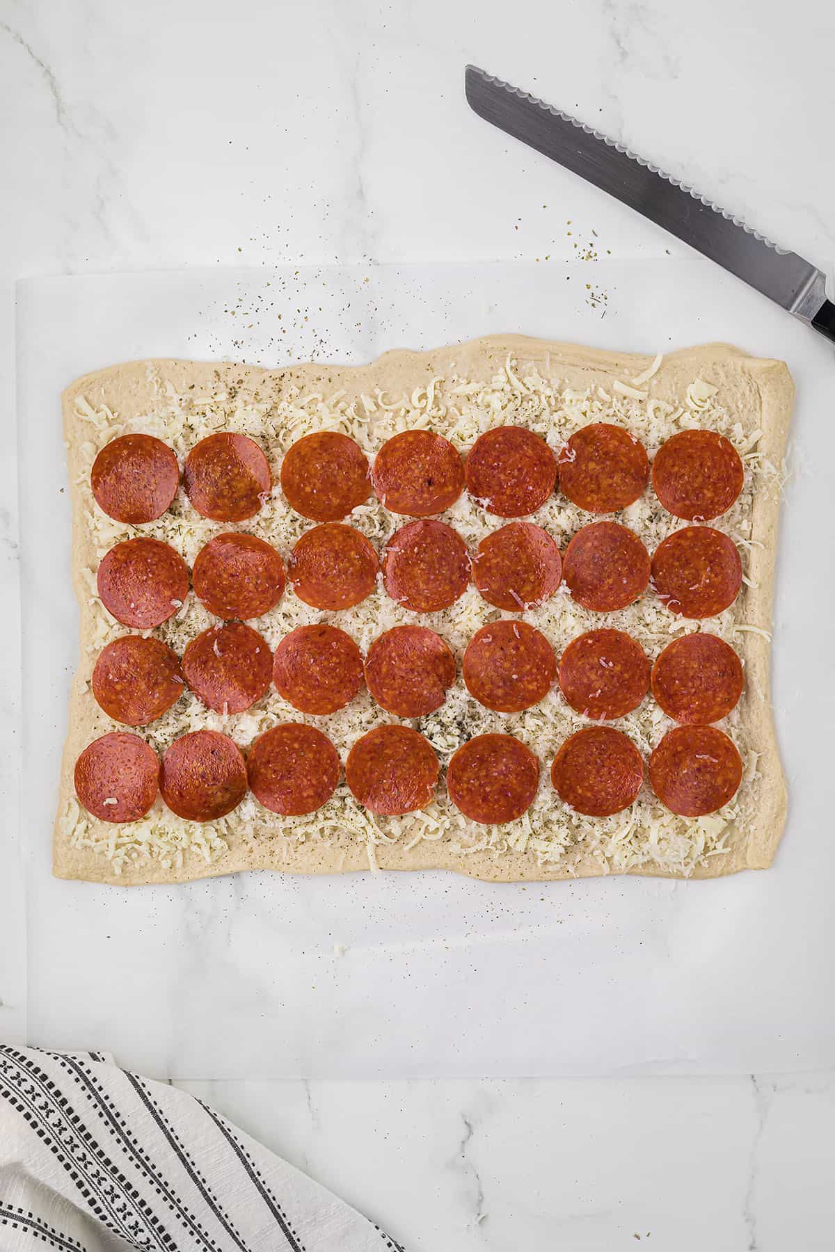 Pizza dough topped with cheese and pepperoni.