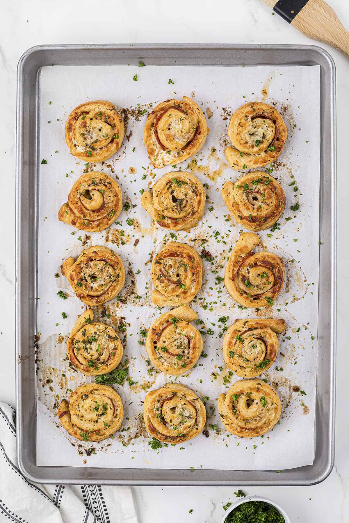 Baked pizza pinwheels on cookie sheet.