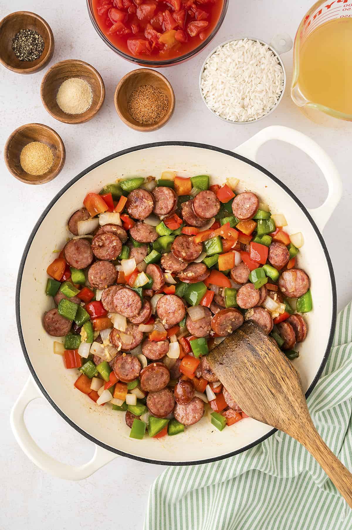Peppers and onions in skillet with andouille sausage.