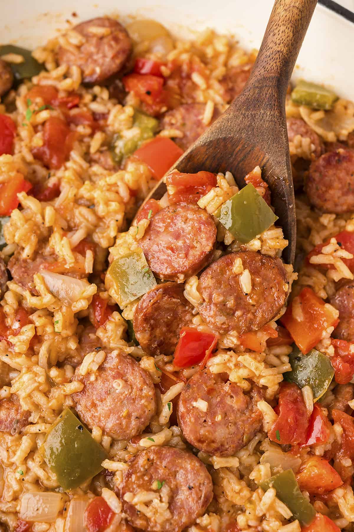 Cajun sausage and rice in a skillet with a wooden spoon.