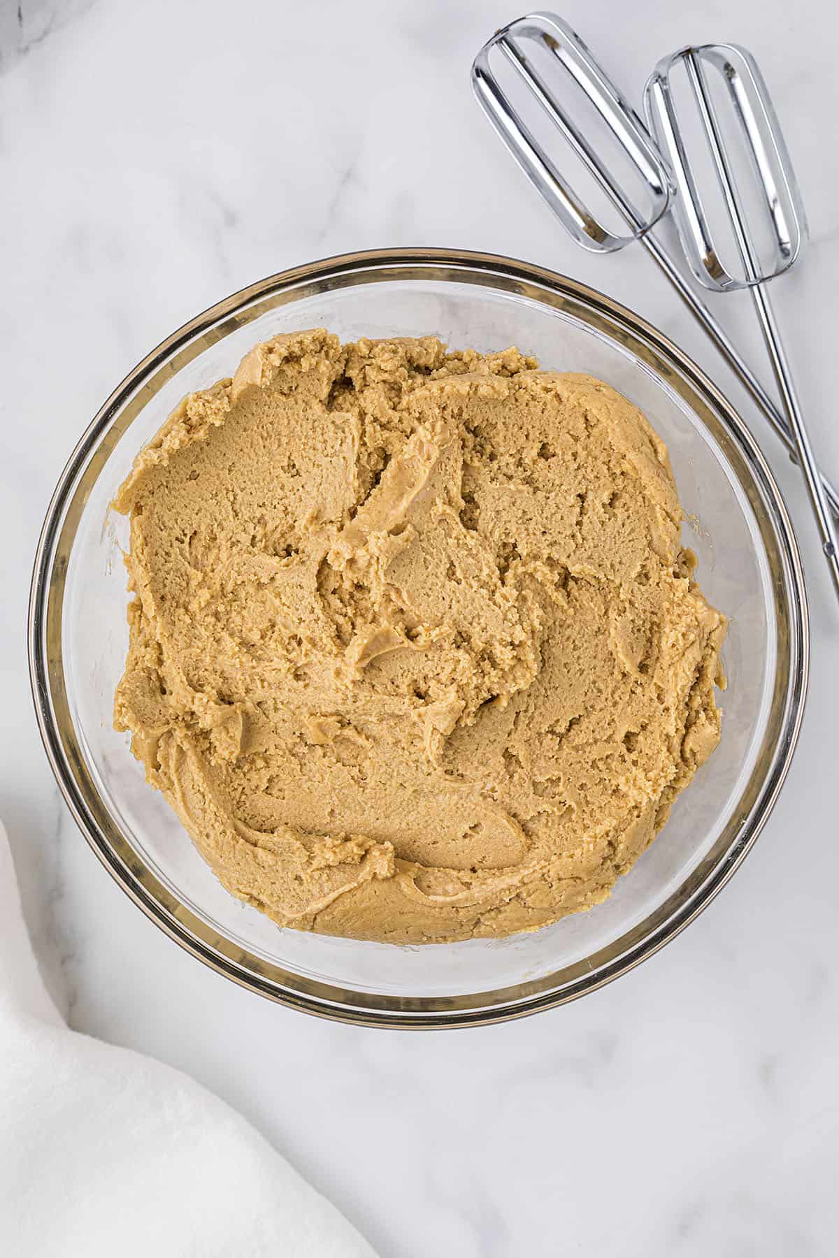 Peanut butter cookie dough in glass mixing bowl.