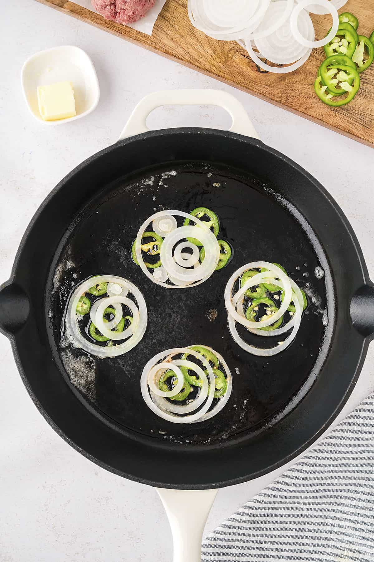 Onion and jalapeno slices in skillet.