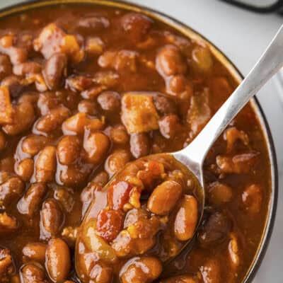 Baked beans on a spoon in a bowl.