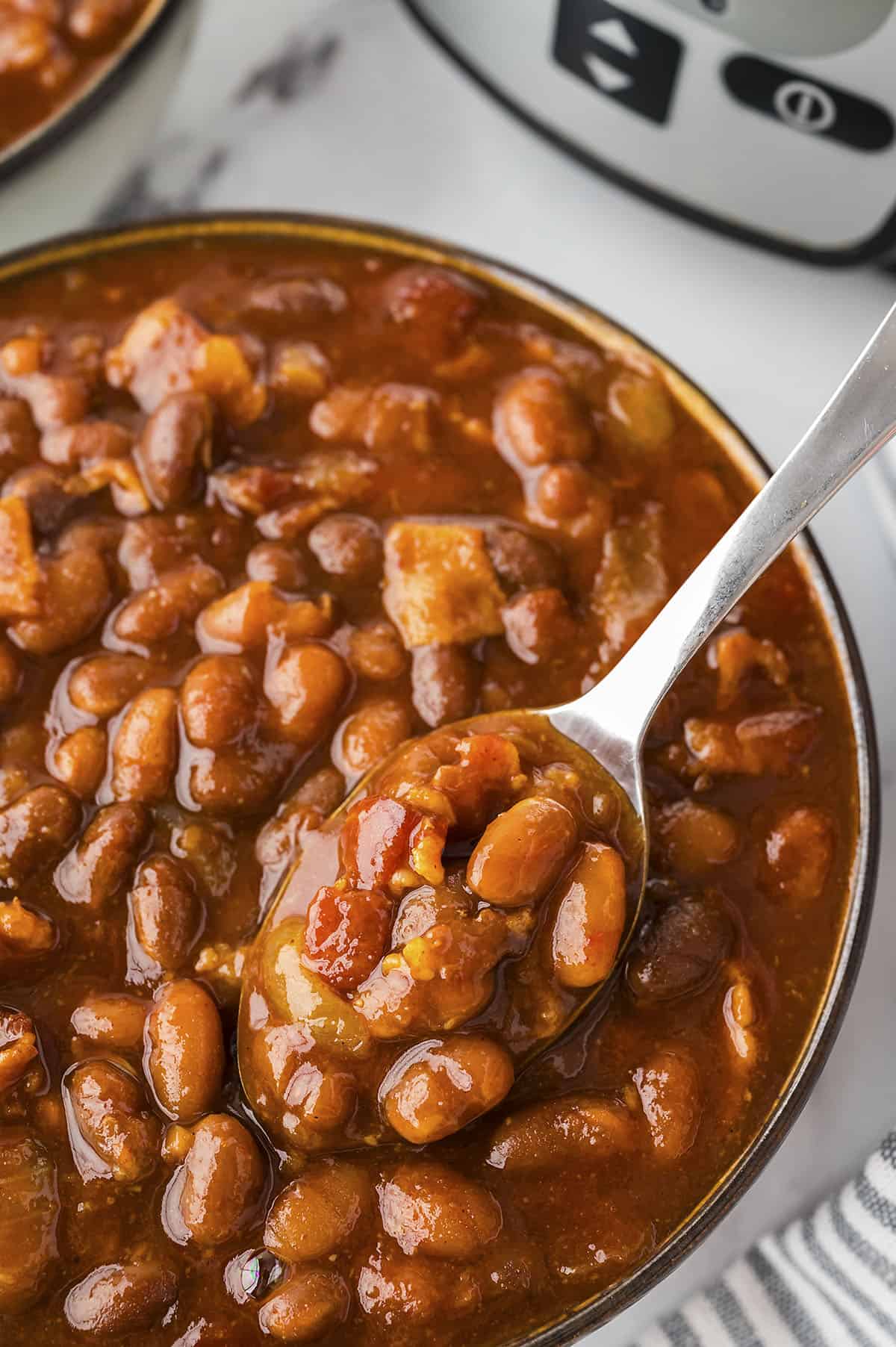 Baked beans on a spoon in a bowl.