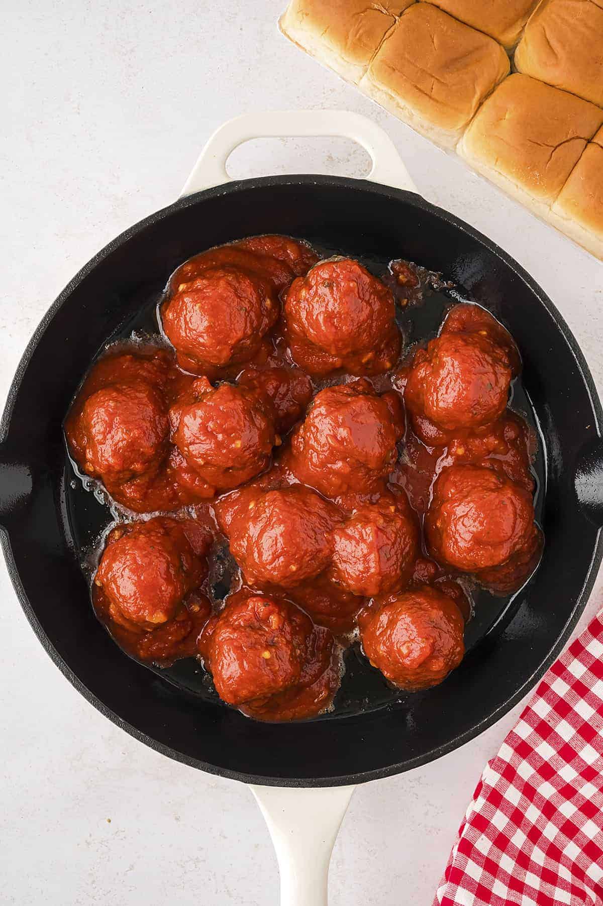Meatballs covered in sauce in skillet.