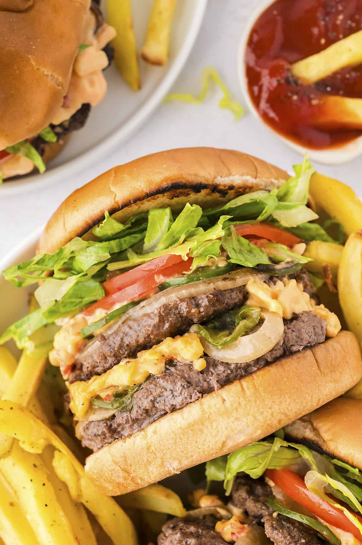 Pimento cheeseburgers surrounded by fries.