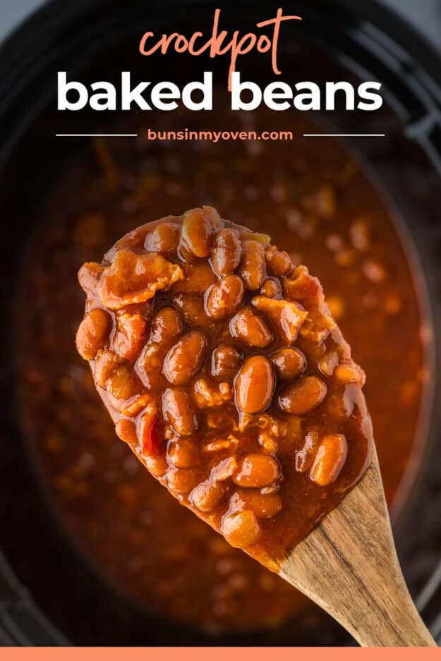 Thick baked beans on wooden spoon over crockpot.