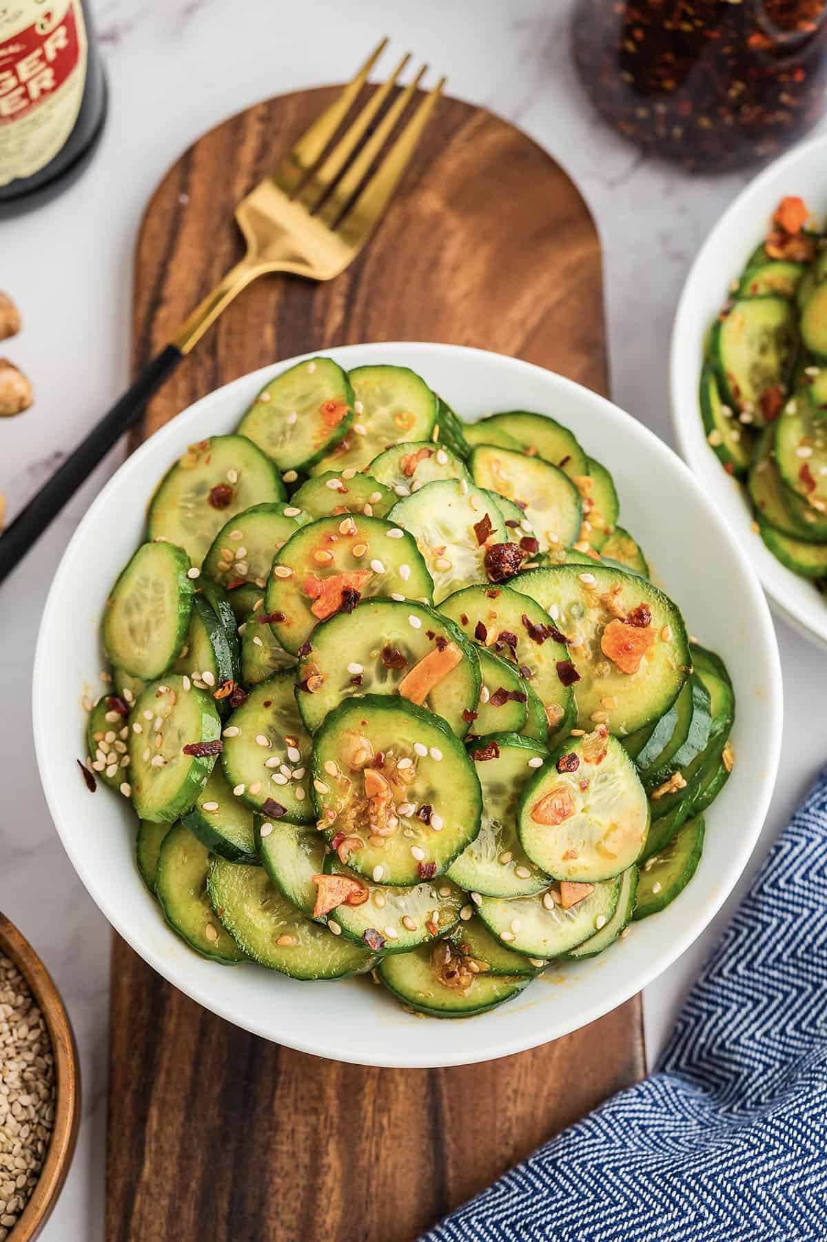 Asian cucumber salad in white bowl on cutting board.