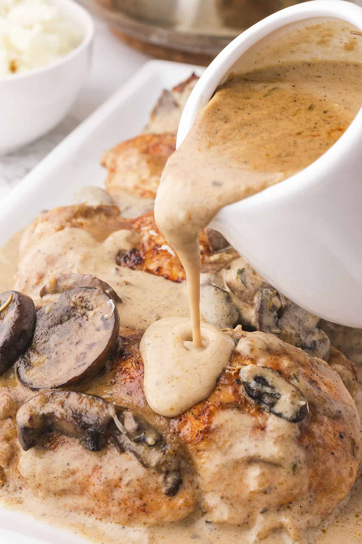 Chicken with cream of mushroom soup being poured over the top.